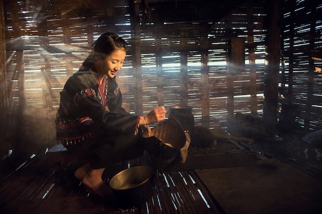 Donna asiatica che cucina alla casa in rurale della Tailandia