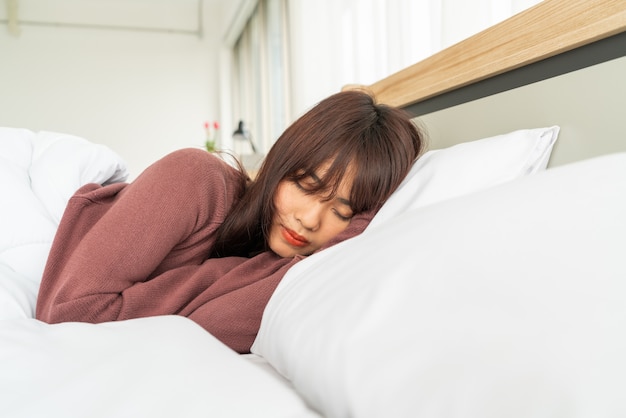 Donna asiatica che dorme sul letto nella mattina