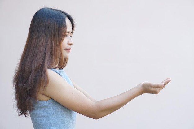 Donna asiatica che estende la mano di lato come tenere un prodotto