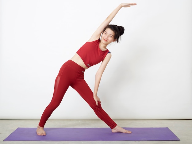 Donna asiatica che fa posa sulla stuoia di yoga, esercitando in studio