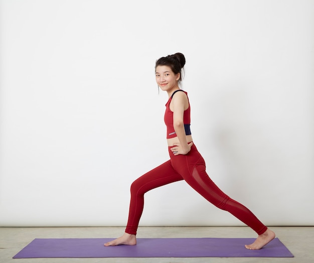 Donna asiatica che fa posa sulla stuoia di yoga, esercitando in studio