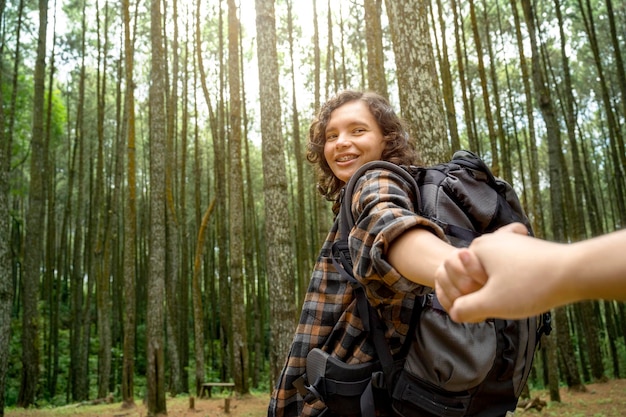 Donna asiatica che fa trekking nella foresta tenendosi per mano