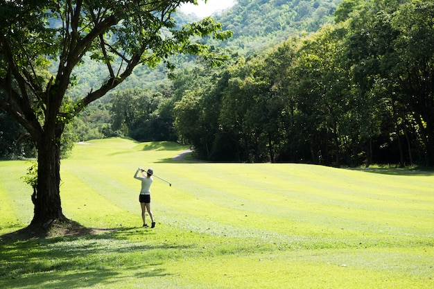 Donna asiatica che gioca a golf su un bello campo da golf naturale