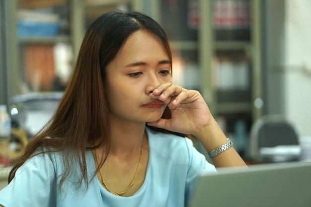 Donna asiatica che guarda il computer Frustrato dal calo dei guadagni