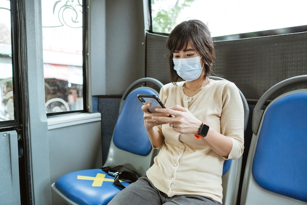 Donna asiatica che guida un trasporto pubblico che indossa la maschera per il viso durante la pandemia