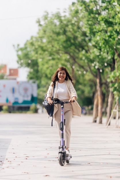 Donna asiatica che guida uno scooter elettrico nel concetto di stile di vita del parco