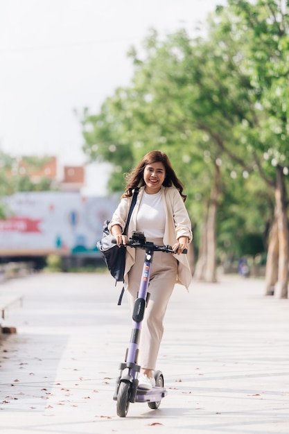 Donna asiatica che guida uno scooter elettrico nel concetto di stile di vita del parco