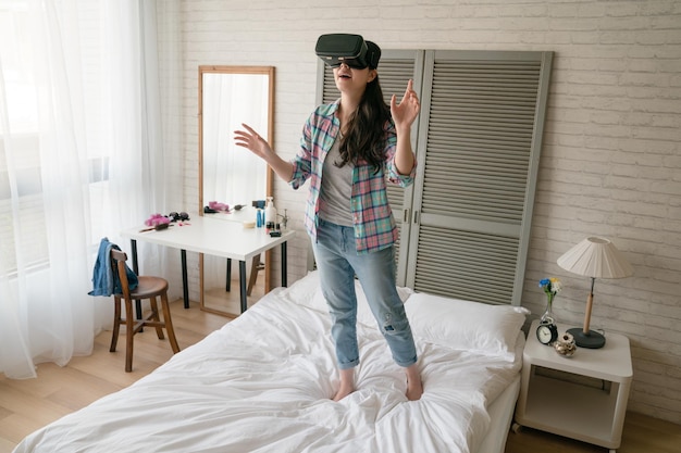Donna asiatica che indossa il dispositivo virtuale e si abbandona a questo mondo virtuale. Alza le mani sembra come afferrare qualcosa nell'aria.