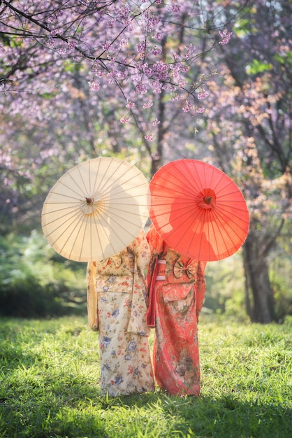 Donna asiatica che indossa il kimono giapponese tradizionale con il fiore rosa