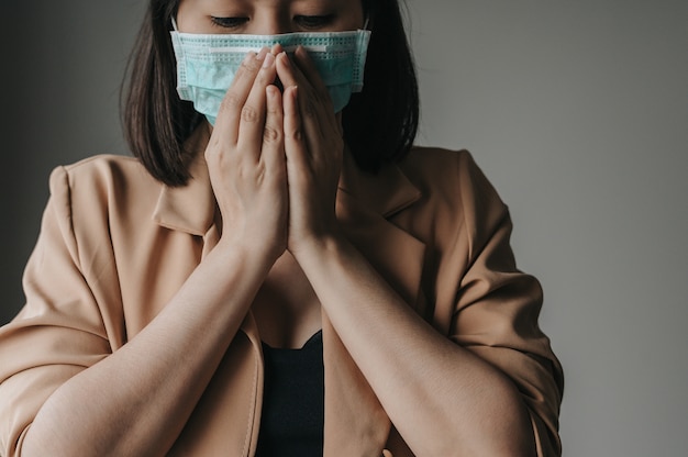 Donna asiatica che indossa tosse protettiva della maschera di protezione