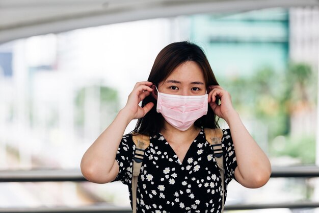 Donna asiatica che indossa una maschera facciale per proteggersi dal virus dell'influenza