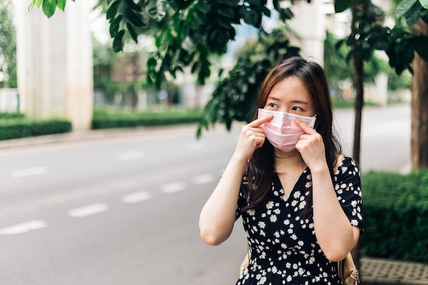 Donna asiatica che indossa una maschera facciale per proteggersi dall'epidemia di Coronavirus COVID19 in città