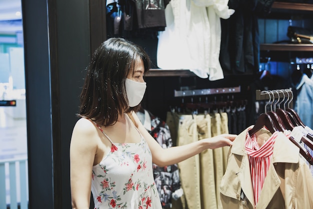 Donna asiatica che indossa una maschera in un posto per lo shopping