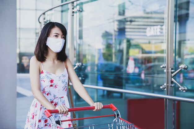 Donna asiatica che indossa una maschera in un posto per lo shopping