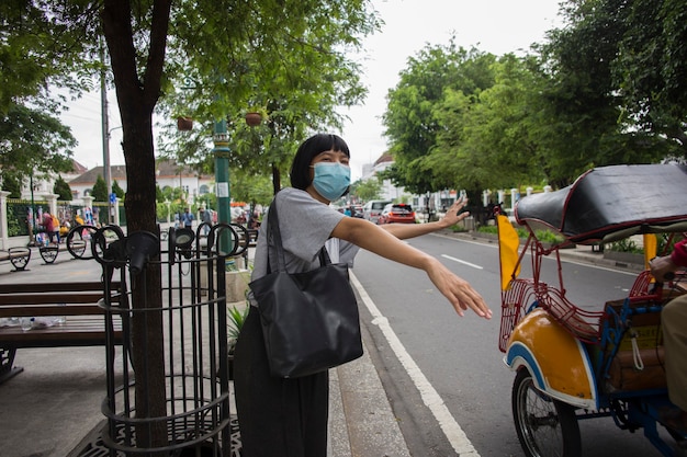 Donna asiatica che indossa una maschera medica in attesa fuori per i trasporti pubblici