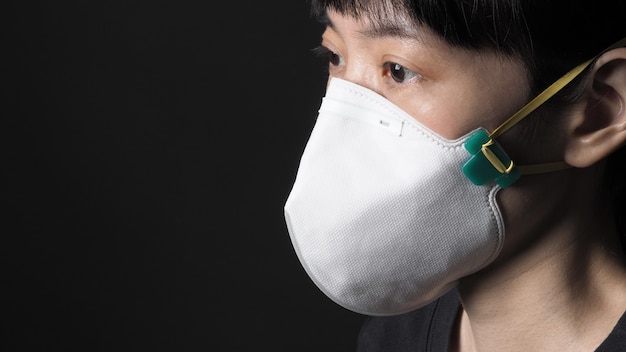 Donna asiatica che indossa una maschera sana n95 per proteggere il coronavirus o covid19 e pm 25 polvere pericolosa