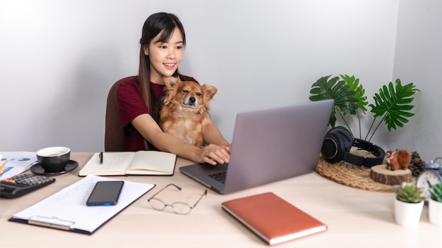 donna asiatica che lavora a distanza da casa utilizzando il computer portatile seduto sul divano