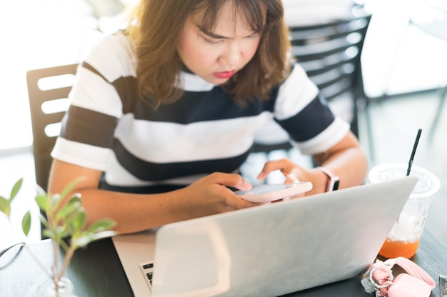 Donna asiatica che lavora con laptop e smartphone