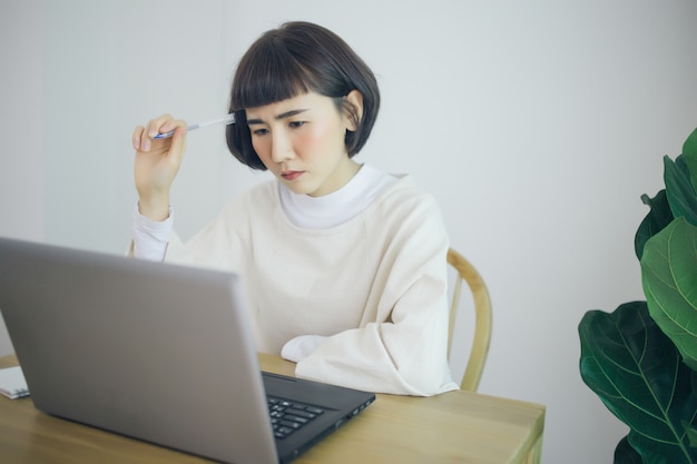 Donna asiatica che lavora da casa. È seria e stressata.