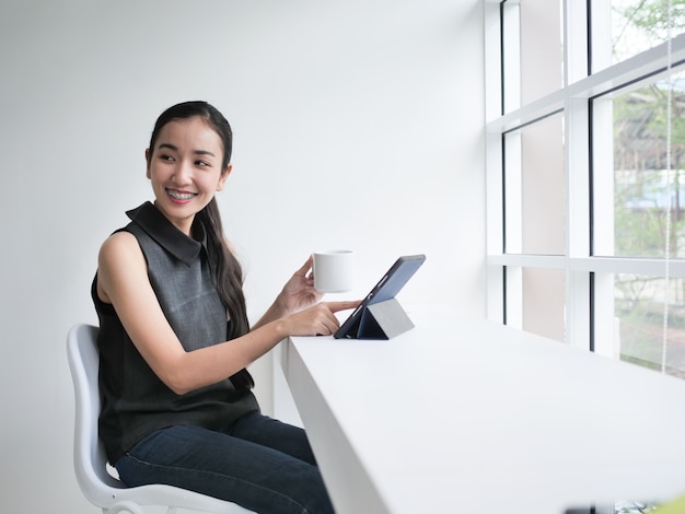 Donna asiatica che lavora in ufficio con il caffè