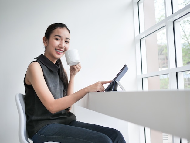 Donna asiatica che lavora in ufficio con il caffè