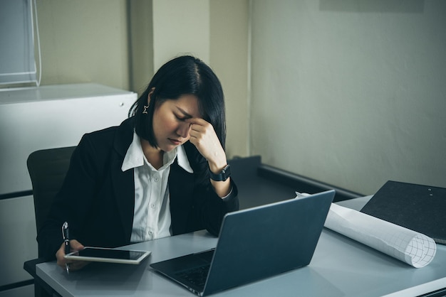 Donna asiatica che lavora in ufficio Giovane donna d'affari stressata dal sovraccarico di lavoro con un sacco di file sulla scrivania La gente della Thailandia pensa qualcosa