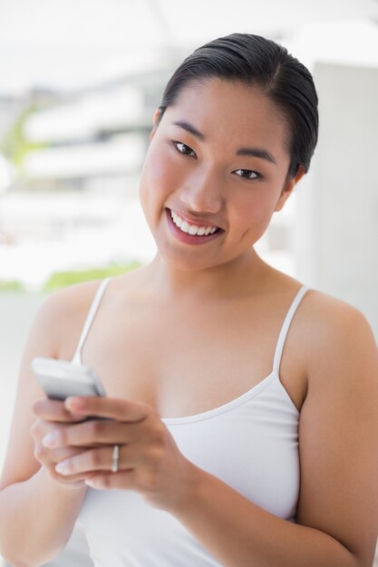 Donna asiatica che manda un sms sul telefono