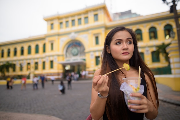 Donna asiatica che mangia davanti all'ufficio postale centrale di Saigon