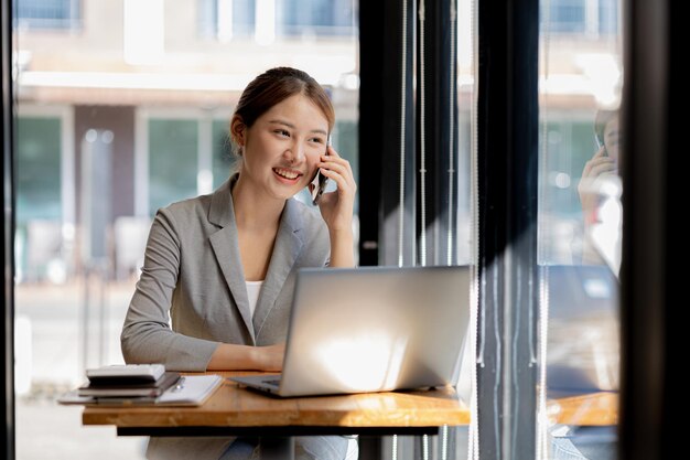 Donna asiatica che parla al telefono è una commessa in una società di avvio sta chiamando i clienti per vendere prodotti e promozioni Concetto di vendita di prodotti tramite canali telefonici