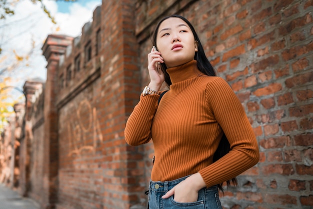 Donna asiatica che parla al telefono.