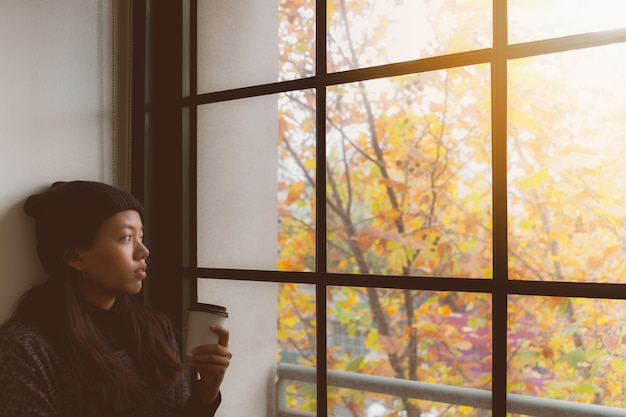 Donna asiatica che pensa mentre beva il caffè e condizione nella sala