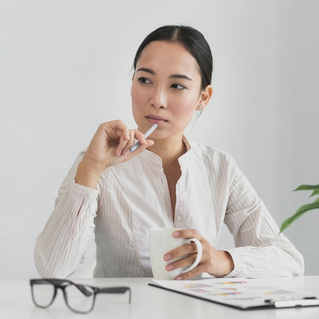 Donna asiatica che pensa nell'ufficio