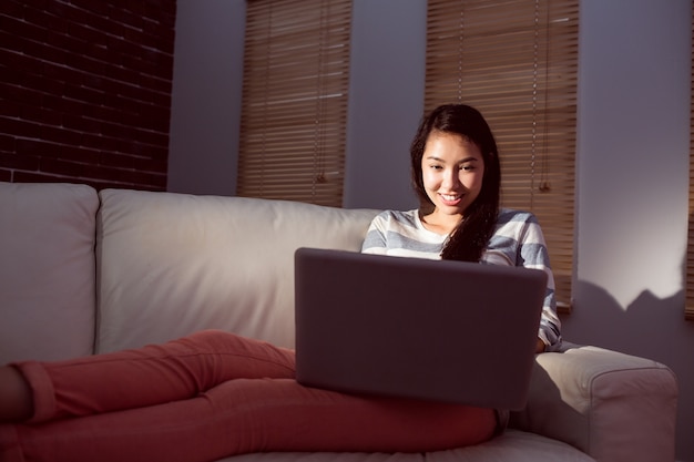 Donna asiatica che per mezzo del computer portatile alla notte