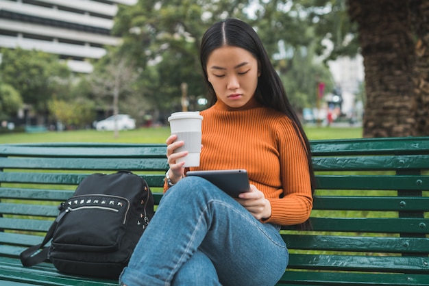 Donna asiatica che per mezzo della sua compressa digitale