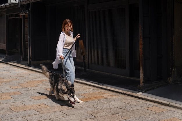 Donna asiatica che porta a spasso il suo cane husky all'aperto