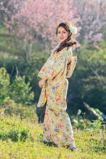 Donna asiatica che porta kimono tradizionale giapponese al giardino di sakura.