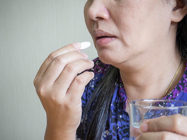 Donna asiatica che prende e mangia vitamina e medicina