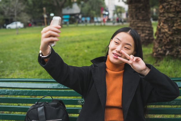 Donna asiatica che prende selfie con il telefono.