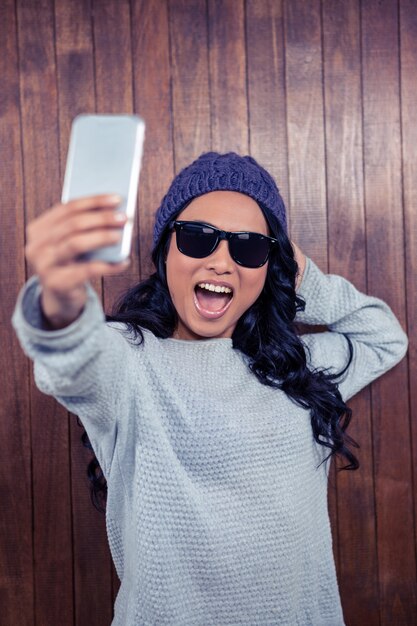 Donna asiatica che prende selfie contro la parete di legno