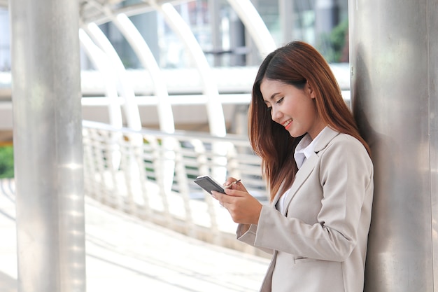 Donna asiatica che punta al telefono cellulare. Lavoratori freelance.