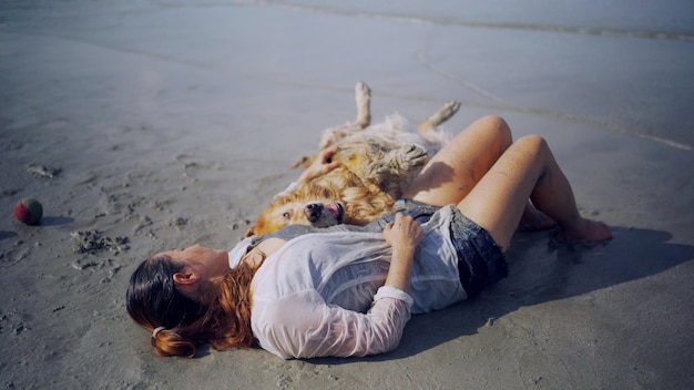 Donna asiatica che si rilassa con il cane sulla spiaggia Ricreazione e stile di vita del Golden Retriever durante le vacanze estive.