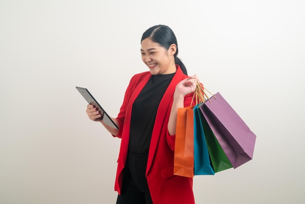 Donna asiatica che tiene borsa della spesa e tablet a portata di mano con sfondo bianco