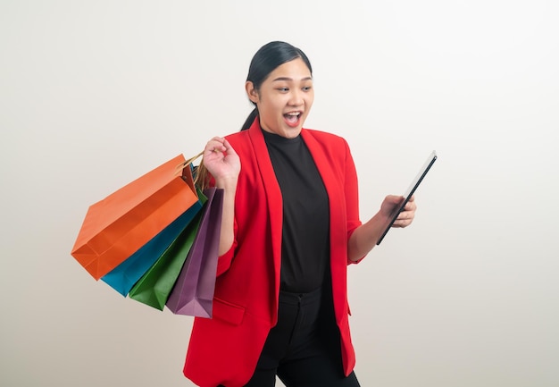 Donna asiatica che tiene borsa della spesa e tablet a portata di mano con sfondo bianco