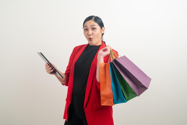 Donna asiatica che tiene borsa della spesa e tablet a portata di mano con sfondo bianco