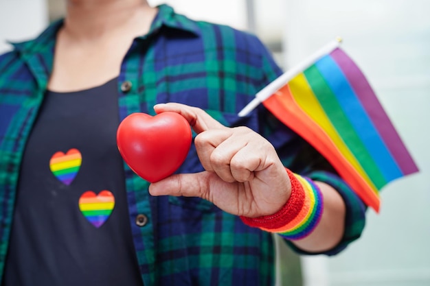 Donna asiatica che tiene rosso hert con bandiera arcobaleno LGBT diritti dei simboli e uguaglianza di genere LGBT Pride Month a giugno