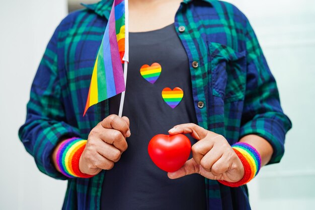 Donna asiatica che tiene rosso hert con bandiera arcobaleno LGBT diritti dei simboli e uguaglianza di genere LGBT Pride Month a giugno