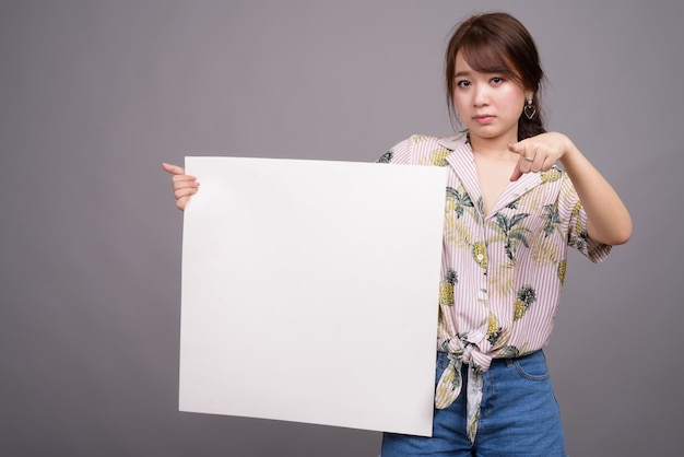 Donna asiatica che tiene scheda bianca vuota con copyspace