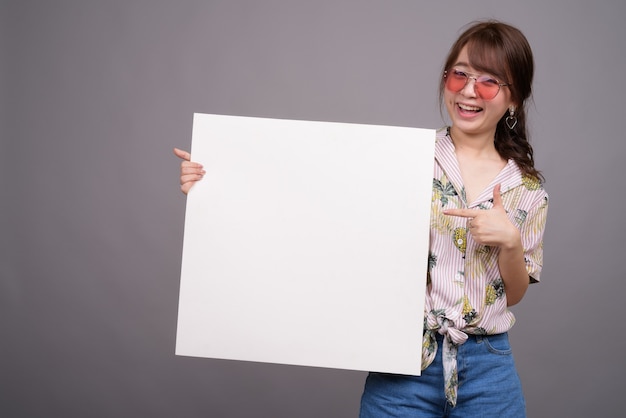 Donna asiatica che tiene scheda bianca vuota con copyspace