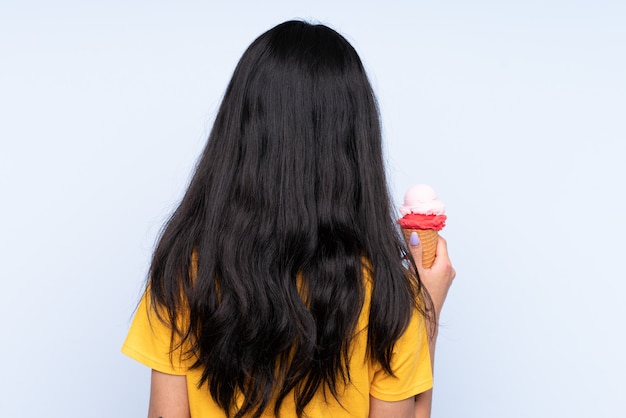 Donna asiatica che tiene un gelato sopra fondo blu isolato