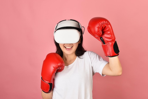 Donna asiatica che usa gli occhiali vr Allenarsi con l'applicazione di videogiochi di boxe dall'auricolare per realtà virtuale La giovane donna gode di una nuova esperienza di fitness con la tecnologia vr Studio girato